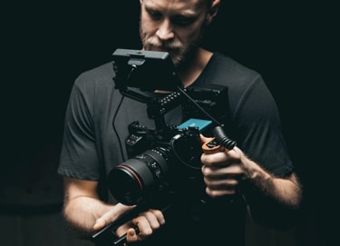  a man looking into the viewfinder of a camera while holding it